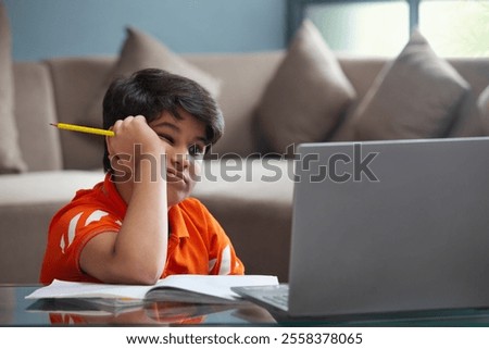 A YOUNG BOY TRYING TO CONCENTRATE DURING ONLINE CLASS