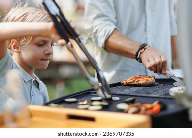 Young boy turning grilled vegetables with tongs. - Powered by Shutterstock