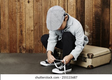 Young Boy Tying Shoelace Sitting On Suitcase