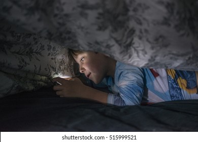 Young Boy Under Duvet With Cell Phone