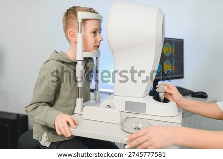 Young boy undergoing a vision test using an autorefractor instrument. Pediatric patient checking eye health with medical equipment