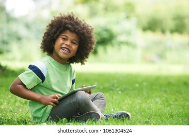 Young Boy Using Digital Tablet In Park - Powered by Shutterstock