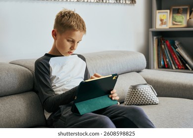 Young boy using digital tablet on sofa at home - Powered by Shutterstock - Get 15% off with code: PIKWIZARD15
