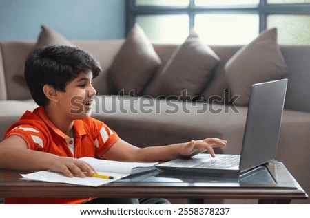 A YOUNG BOY USING LAPTOP TO ATTEND ONLINE CLASS