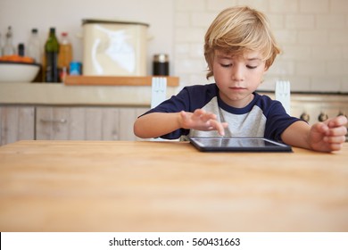 Young boy using tablet computer at kitchen table, front view - Powered by Shutterstock