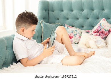 Young boy using tablet lying down on couch at home 