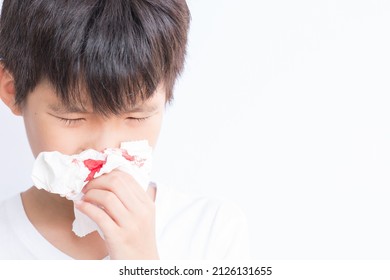 Young boy using tissue to stop nose from bleeding. Isolated in white background. 