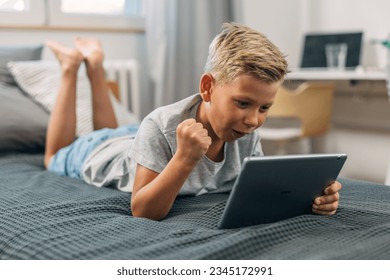 Young boy is watching a sports game on a tablet. - Powered by Shutterstock