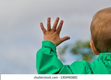 Young Boy Waving His Left Hand, Seen From Behind.