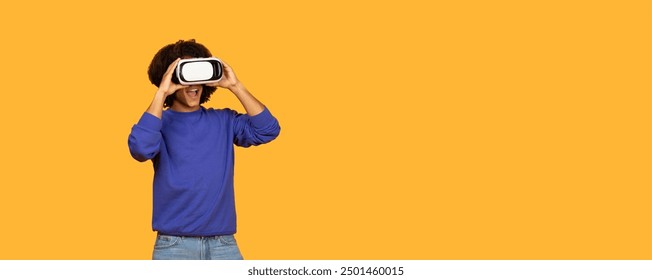 A young boy wearing a blue sweater is engaged in an exciting experience with a virtual reality headset. He is joyful and enthusiastic as he interacts with a digital world, copy space - Powered by Shutterstock