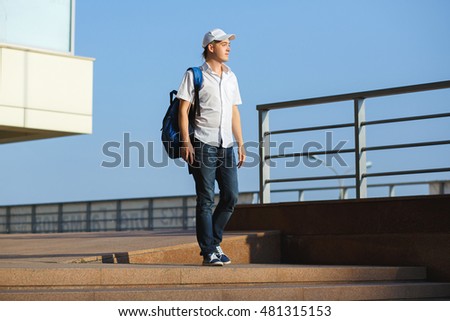 A young boy wearing a cap with a backpack walking through the city