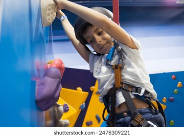 Young boy wearing helmet climbing wall in gym. - Powered by Shutterstock