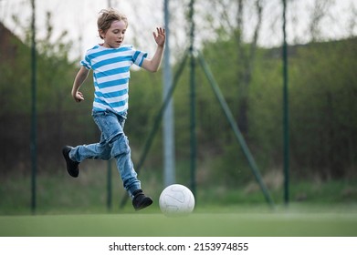 Young Boy Wearing Jeans And T-shirt Plays Soccer