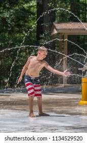 A Young Boy Wearing Red, White And Blue Plays On The Splash Pad At Tickfaw State Park In Livingston Parish, Louisiana