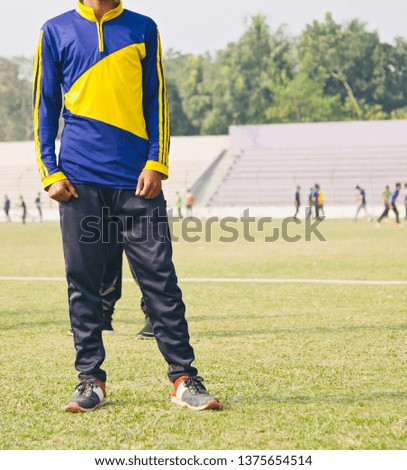 Young boy wearing trousers standing in a sports ground unique photo