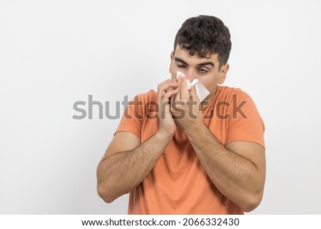 a young boy wiping his snot because he is sick on a white background.