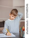 Young boy writing and thinking at the same time, front view
