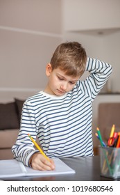 Young boy writing and thinking at the same time, front view