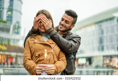 Young Boyfriend Is Covering His Woman Eyes Doing A Surprise - Beautiful Woman Making A Wish Holding Firework - Love And Gift Concept - Focus On Man Hands - Warm Filter With Soft Vivid Editing