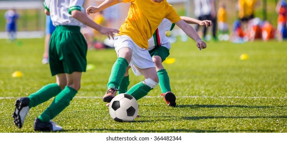 Young Boys Of Football Academy Playing Football Soccer Game. Running Players In Colorful Uniforms