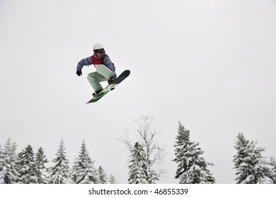 Young Boys Jumping In Air Ind Showing Trick With Snowboard At Winter Season