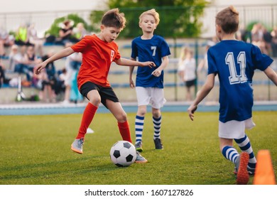 Young Boys Playing Soccer Game. Training And Football Match Between Youth Soccer Teams. Junior Competition Between Players Running And Kicking Soccer Ball. Final Game Of Football Tournament For Kids
