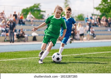 Young Boys Playing Soccer Game. Kids Having Fun In Sport. Happy Kids Compete In Football Game. Running Soccer Players. Competition Between Players Running And Kicking Football Ball. Football School