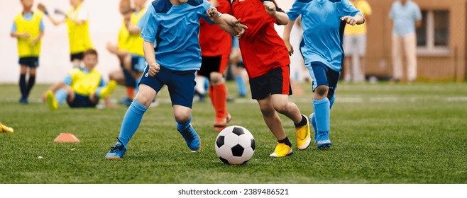 Young boys playing soccer game. Kids having fun in sport. Happy kids compete in football game.. Running soccer players. Competition between players running and kicking football ball. Football school - Powered by Shutterstock