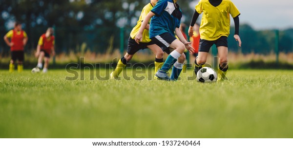 Young boys playing soccer game. Kids having fun in\
sport. Happy kids compete in football game. Running soccer players.\
Competition between players running and kicking football ball.\
Football school