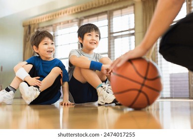 Young boys practising on a basketball court with a young male coach. - Powered by Shutterstock