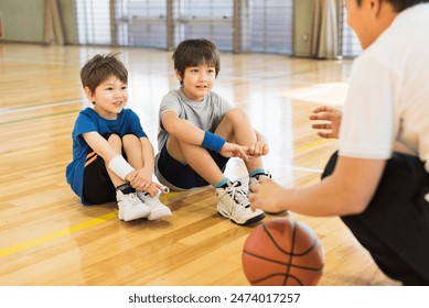 Young boys practising on a basketball court with a young male coach. - Powered by Shutterstock