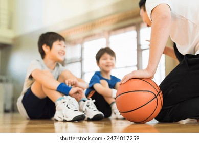 Young boys practising on a basketball court with a young male coach. - Powered by Shutterstock