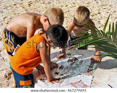 Young boys reading a pirate treasure map on the beach in Mexico