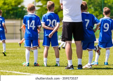 Young Boys And Soccer Coach Watching Football Match. Youth Reserve Players Ready To Play