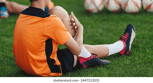 Young Boys in Sports Uniform Sitting and Stretching on Grass Field. Kids in Soccer Club on Training Unit. Kids Play Team Sports. Boy Pulling Knee To Chest During Soccer Fitness Session - Powered by Shutterstock