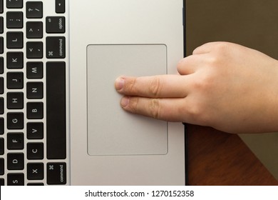 Young boys using a laptop track pad with two fingers.