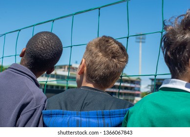 Young Boys Watching Cricket Match Through Fence