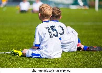 Young Boys Watching Football Match. Youth Reserve Players Sitting On A Soccer Pitch Ready To Play Football Tournament.