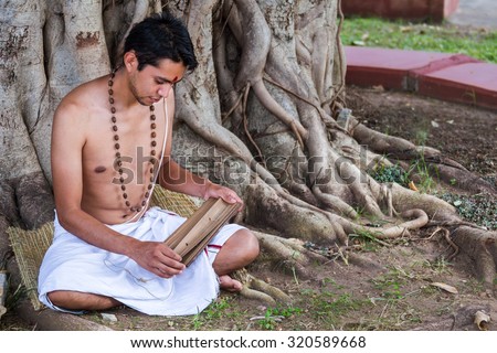 A young brahmin reads an ancient Hindu text under a banyan tree.
 Stock photo © 