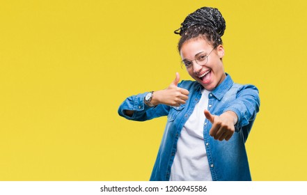 Young braided hair african american girl wearing glasses over isolated background approving doing positive gesture with hand, thumbs up smiling and happy for success. Looking at the camera, winner  - Powered by Shutterstock