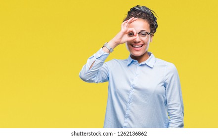 Young braided hair african american business girl wearing glasses over isolated background doing ok gesture with hand smiling, eye looking through fingers with happy face. - Shutterstock ID 1262136862