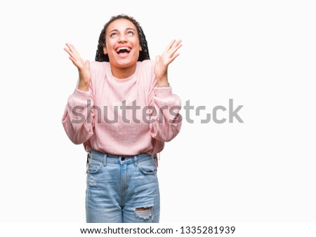 Young braided hair african american girl wearing sweater over isolated background celebrating crazy and amazed for success with arms raised and open eyes screaming excited. Winner concept