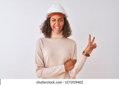 Young brazilian architect woman wearing security helmet over isolated white background smiling with happy face winking at the camera doing victory sign. Number two.