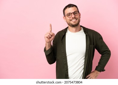 Young Brazilian man isolated on pink background showing and lifting a finger in sign of the best