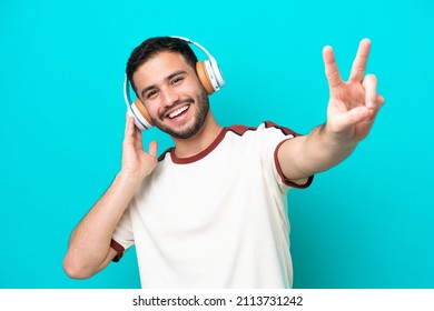 Young Brazilian Man Isolated On Blue Background Listening Music And Singing