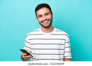 Young Brazilian man isolated on blue background using mobile phone - Shutterstock ID 2113734599