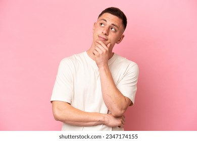 Young Brazilian man isolated on pink background having doubts - Powered by Shutterstock