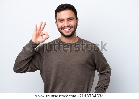 Young Brazilian man isolated on white background showing ok sign with fingers