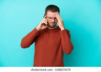 Young Brazilian Man Using Mobile Phone Isolated On Blue Background With Tired And Sick Expression