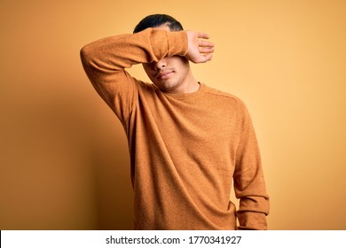Young brazilian man wearing casual sweater standing over isolated yellow background covering eyes with arm, looking serious and sad. Sightless, hiding and rejection concept - Shutterstock ID 1770341927